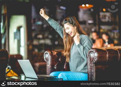 Beautiful Attractive Asian woman celebrating with laptop after success job feeling so happy and cheerful,Business Startup concept