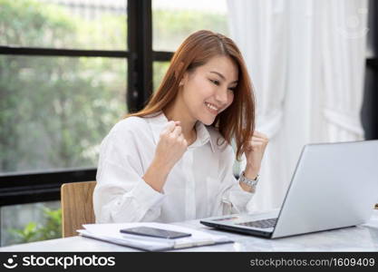 Beautiful Attractive Asian woman celebrating with laptop after success job feeling so happy and cheerful,Business Startup concept 