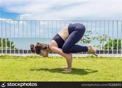 Beautiful Attractive Asian woman practice yoga Baby Bakasana pose stretching exercises muscle for warm up with sea,Feeling so comfortable and relax in holiday