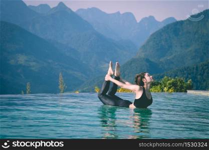 Beautiful Attractive Asian woman practice yoga bow or dhanurasana pose on the pool above the Mountain peak in the morning in front of beautiful nature views in SAPA vietnam,Feel so comfortable