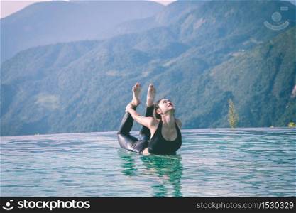 Beautiful Attractive Asian woman practice yoga bow or dhanurasana pose on the pool above the Mountain peak in the morning in front of beautiful nature views in SAPA vietnam,Feel so comfortable