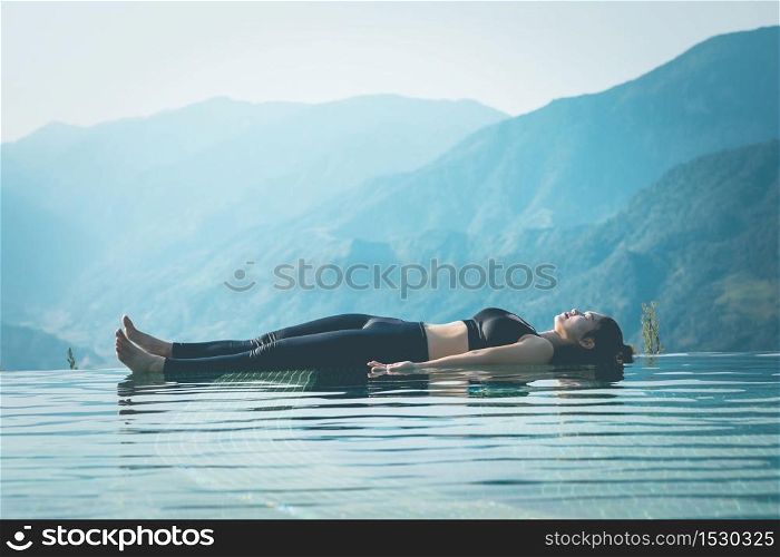 Beautiful Attractive Asian woman practice yoga Dead Body or Savasana on the pool above the Mountain peak in the morning in front of beautiful nature views in SAPA vietnam,Feel so comfortable