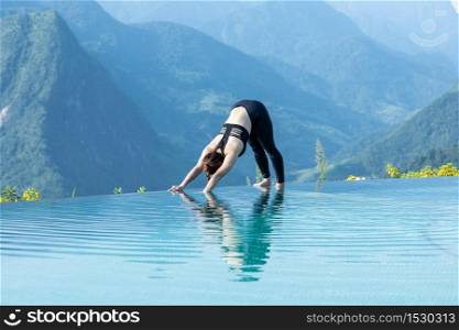 Beautiful Attractive Asian woman practice yoga Downward Facing Dog or Adho Mukha Svanasana pose on the pool above the Mountain peak in the morning in front of beautiful nature views in SAPA vietnam