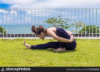 Beautiful Attractive Asian woman practice yoga paschimottanasana pose stretching exercises muscle for warm up with sea,Feeling so comfortable and relax in holiday