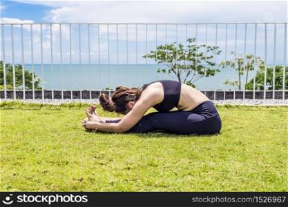 Beautiful Attractive Asian woman practice yoga paschimottanasana pose stretching exercises muscle for warm up with sea,Feeling so comfortable and relax in holiday