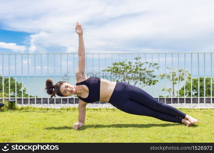 Beautiful Attractive Asian woman practice yoga side plank pose stretching exercises muscle for warm up with sea,Feeling so comfortable and relax in holiday