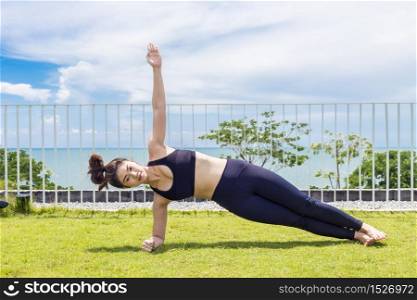 Beautiful Attractive Asian woman practice yoga side plank pose stretching exercises muscle for warm up with sea,Feeling so comfortable and relax in holiday