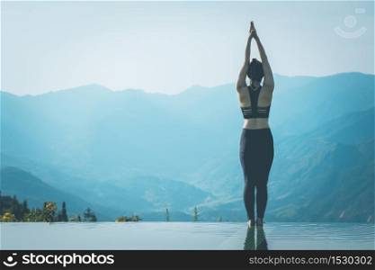 Beautiful Attractive Asian woman practice yoga Surya Namaskar exercise Ekam pose on the pool above the Mountain peak in the morning in front of beautiful nature views in SAPA vietnam,Feel comfortable