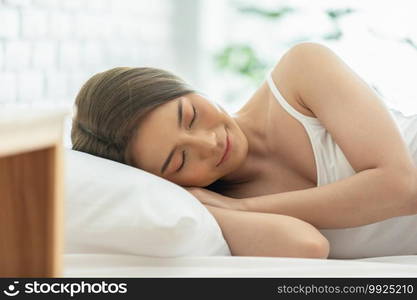 Beautiful Attractive Asian woman wearing Pajamas sleep close her eyes smile sleep and sweet dream on bed in bedroom in the morning feeling so relax and comfortable,Healthcare and Sleep Concept