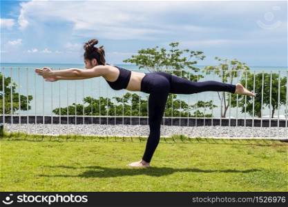 Beautiful Attractive Asian young woman practice Balancing stick Pose stretching exercises muscle for warm up with sea,Feeling so comfortable and relax in holiday