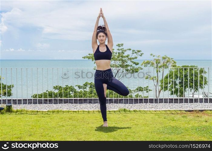 Beautiful Attractive Asian young woman practice Tree Pose stretching exercises muscle for warm up with sea,Feeling so comfortable and relax in holiday
