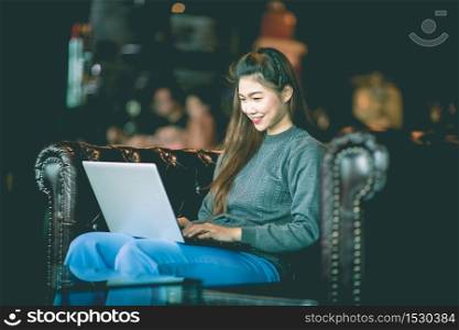 Beautiful Attractive Business Asian woman sitting on sofa working with laptop and looking in monitor smile and have positive emotional feeling so happiness,Business Startup Concept