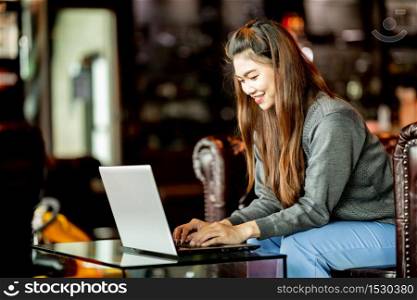 Beautiful Attractive Business Asian woman working with laptop and looking in monitor smile and have positive emotional feeling so happiness,Business Startup Concept,Warm Tone