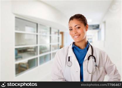 Beautiful attractive happy smiling female doctor physician nurse standing in hospital corridor hall way in front of patient consulting waiting area room.