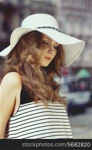 Beautiful, attractive woman in summer hat on the street in summer day she keep her eyes closed. sunset on face&#xA;