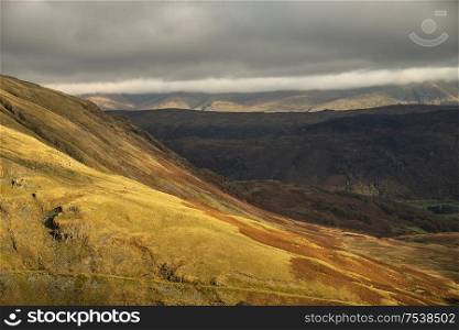 Beautiful Autumn Fall landscape of Lake District hills and countryisde with sunlight hitting hillside