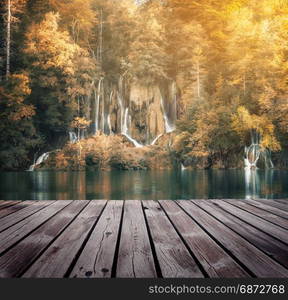 Beautiful autumn forest waterfall with wooden path on foreground. Plitvice National Park, Croatia.