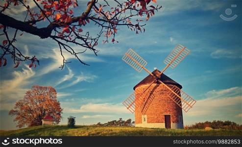 Beautiful autumn landscape with old windmill at sunset and beautiful blue sky with clouds. Colorful nature background on autumn season. Chvalkovice - Czech Republic.