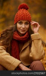 Beautiful autumn portrait of woman in forest or park with orange fall foliage on blurred background. Beautiful autumn portrait of woman in forest