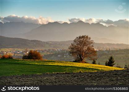 Beautiful autumn sunny evening panorama. Tatras mountains on background, Poland. Rural scene. Small town and village on the hills