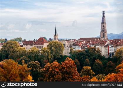 Beautiful Autumn tree foliage with Aare river and Evangelical Church tower view in Bern old town area, Switzerland