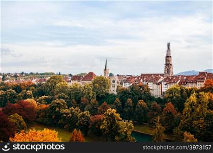 Beautiful Autumn tree foliage with Aare river and Evangelical Church tower view in Bern old town area, Switzerland