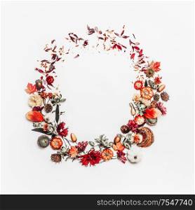 Beautiful autumn wreath or circle frame made with pretty fall leaves, chestnuts, nuts, acorns and flowers on white background. Top view. Flat lay. Creative layout