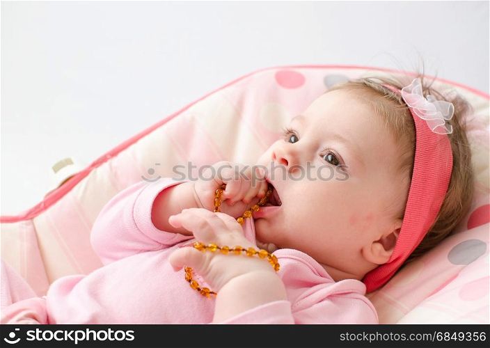 beautiful baby girl chewing amber teething necklace