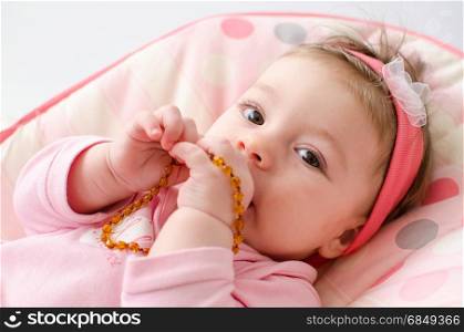 beautiful baby girl chewing amber teething necklace