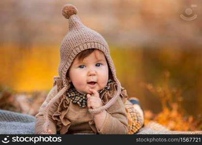 Beautiful baby girl sitting on the plaid near pond. Child outdoor. Baby at picnic in autumn park on sunny day. Pretty little girl. Beautiful baby girl sitting on the plaid near pond. Child outdoor. Baby at picnic in autumn park on sunny day. Pretty little girl.