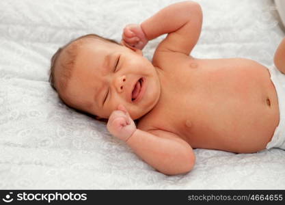 Beautiful baby in diaper lying on a gray blanket crying