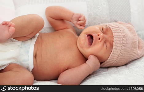 Beautiful baby in diaper with wool cap crying