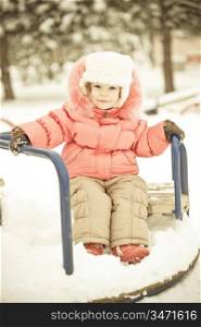 Beautiful baby playing on snow in winter park. Full length portrait, vintage toned
