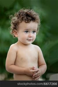 Beautiful baby with curly hair in the garden without t-shirt