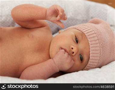 Beautiful baby with wool cap sucking her hand