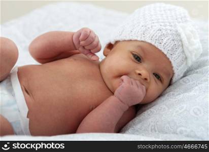 Beautiful baby with wool cap sucking her hand