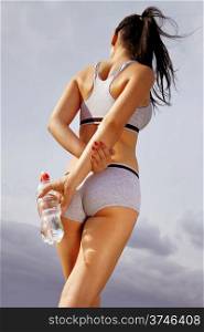 beautiful back of athletic woman that holds bottle of water