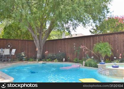 Beautiful back yard pool in summertime, with floats, spa, and great landscaping.