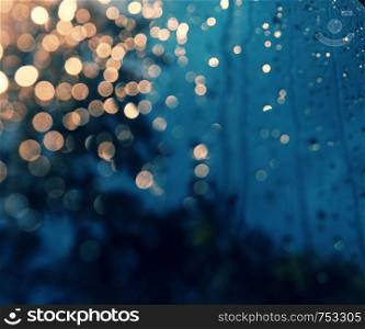 Beautiful background with rain drop on window, traffic light with close up shoot of car glass at night make bokeh in cyan and yellow color