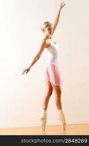 Beautiful ballerina on tiptoe with raised arm dancing pointe
