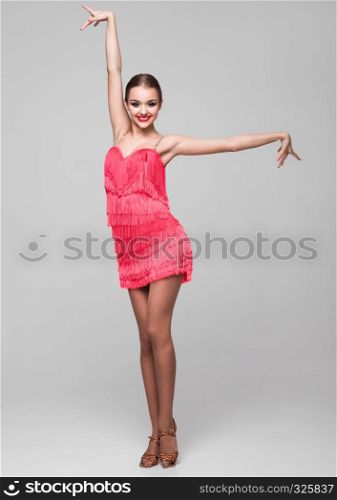 Beautiful ballroom dancer girl in elegant pose red dress on grey background