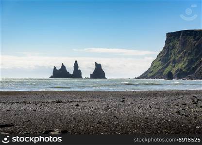 Beautiful Basalt rock Troll on black beach with blue sky, Reynisdrangar, Vik, Iceland