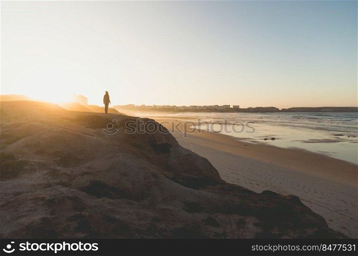 Beautiful beach with a woman walking over the cliff