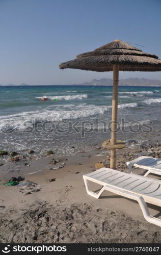 beautiful beach with umbrella and chairs in Kos, Greece (Turkey on the background)