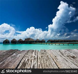 Beautiful beach with water bungalows and old wooden pier at Maldives