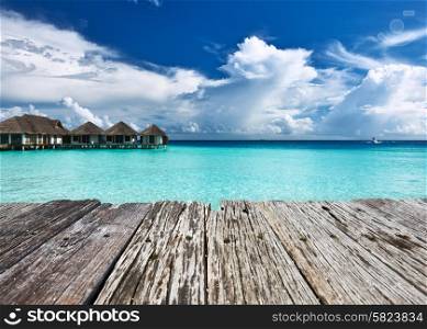 Beautiful beach with water bungalows and old wooden pier at Maldives