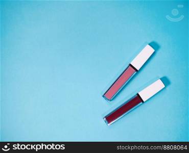 beautiful beige and red lip glosses, isolated on blue background.