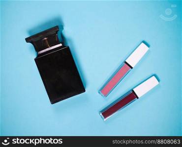 beautiful beige and red lip glosses with perfume bottle, isolated on blue background.