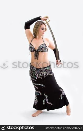 Beautiful belly dancer in black outfit holding sword, isolated