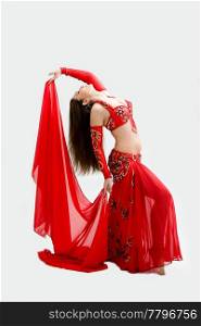 Beautiful belly dancer in red outfit holding veil hanging backward, isolated